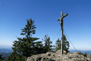 Hochkreuz auf Berggipfel mit Blick auf die Berge im Hintergrund.