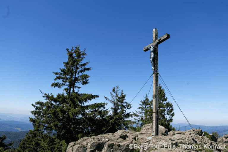 Hochkreuz auf Berggipfel mit Blick auf die Berge im Hintergrund.