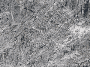 Bergsteiger beim Klettern an einer steilen, felsigen Wand in den Bergen.