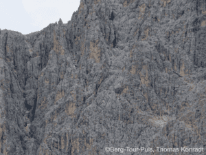 Bergsteiger auf steiler Felswand in den Bergen.