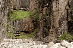 Bergtour in einer beeindruckenden Felsenschlucht mit steilen Wänden und grünen Pflanzen.
