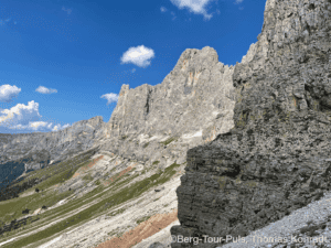 Alpenlandschaft mit steilen Felswänden und blauer Himmel.