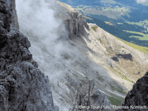 Geysire im Vulkangebiet mit aufsteigendem Dampf, umgeben von felsiger Landschaft.