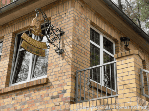 Bergtour-Puls.de, traditionelles Haus mit Balkon und schmiedeeisernem Geländer in ländlicher Umgebun.